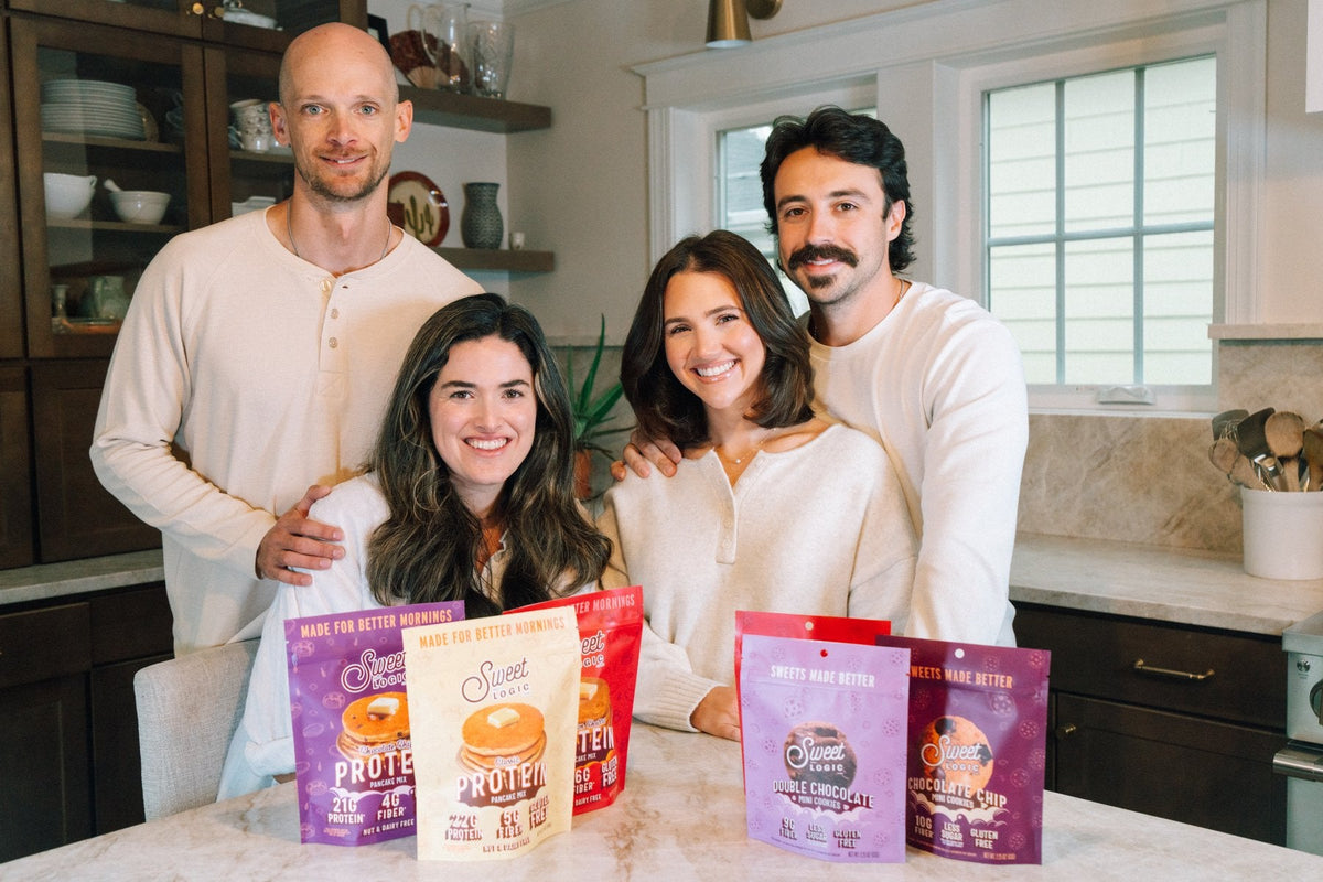 Alli, Matt, Devin and Hunter in the kitchen, holding Sweet Logic pancake and cookie pouches